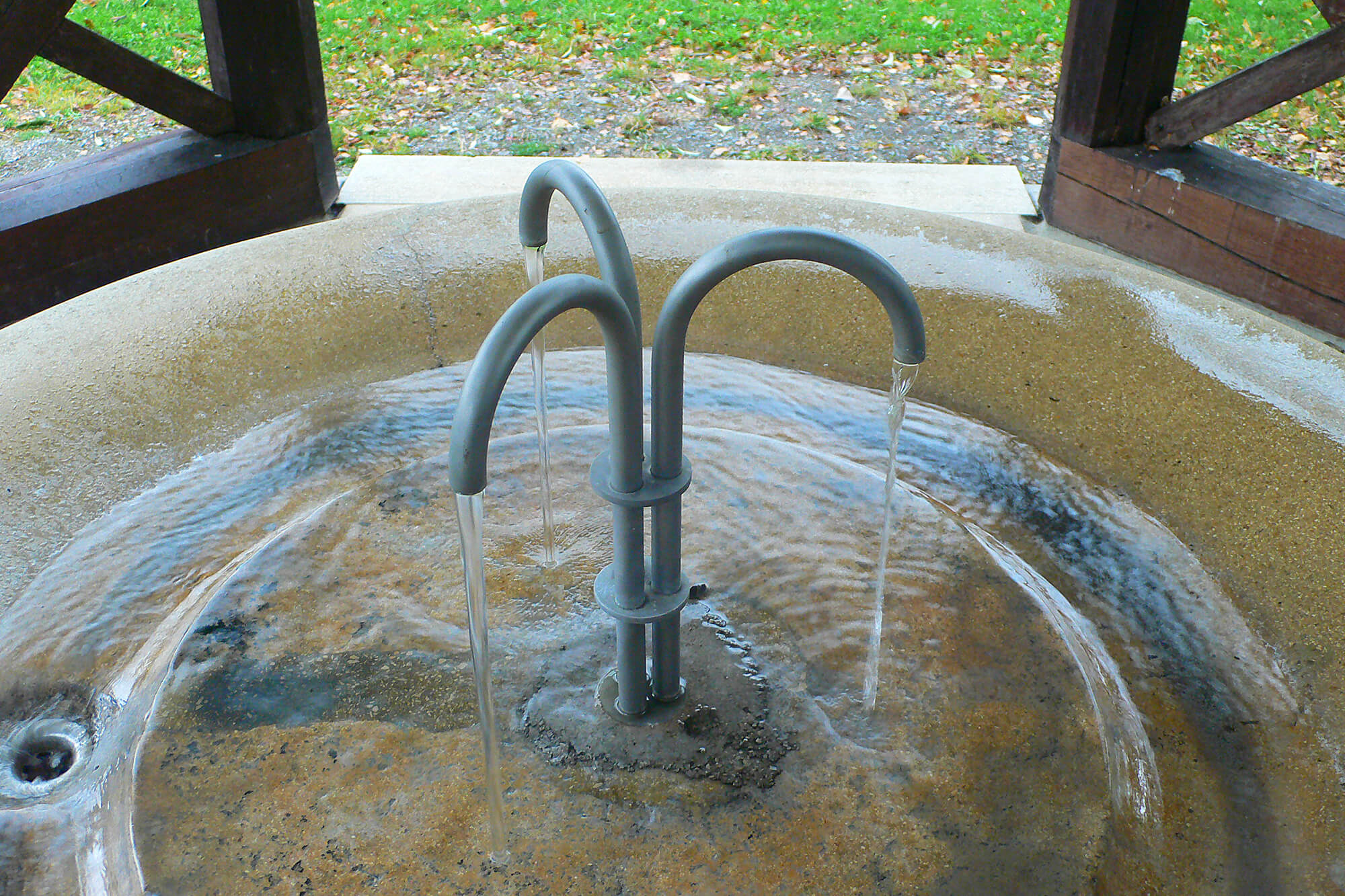 Brunnen mit drei Rohren, aus denen das Schwefelwasser in ein rundes Becken fließt